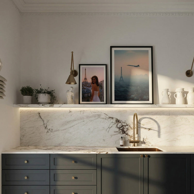 Modern kitchen with dark green cabinets, marble countertop, and framed pictures on the wall.