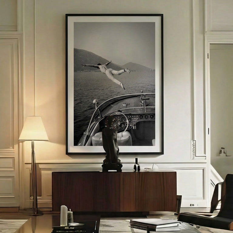 Framed black and white artwork of a person diving into water, displayed on a wall above a wooden console table.