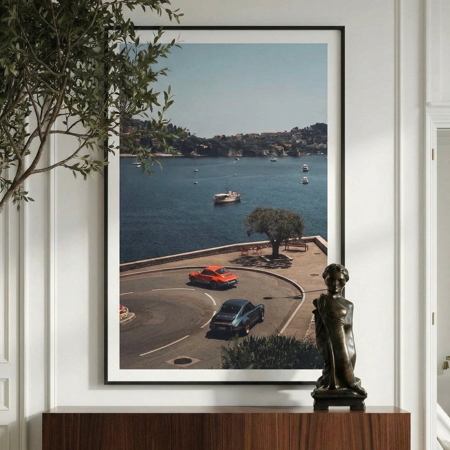Framed photograph of a coastal scene with boats and cars, displayed on a wall above a wooden console table.