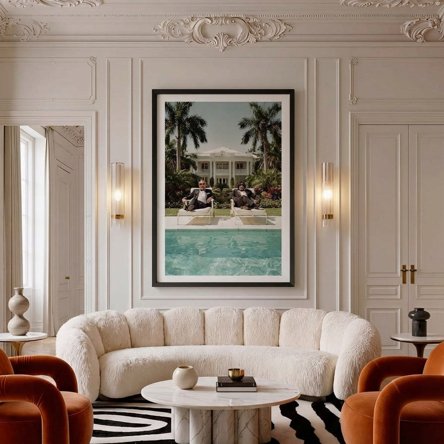 Luxurious living room with a white sofa, orange armchairs, and a framed picture of a pool.
