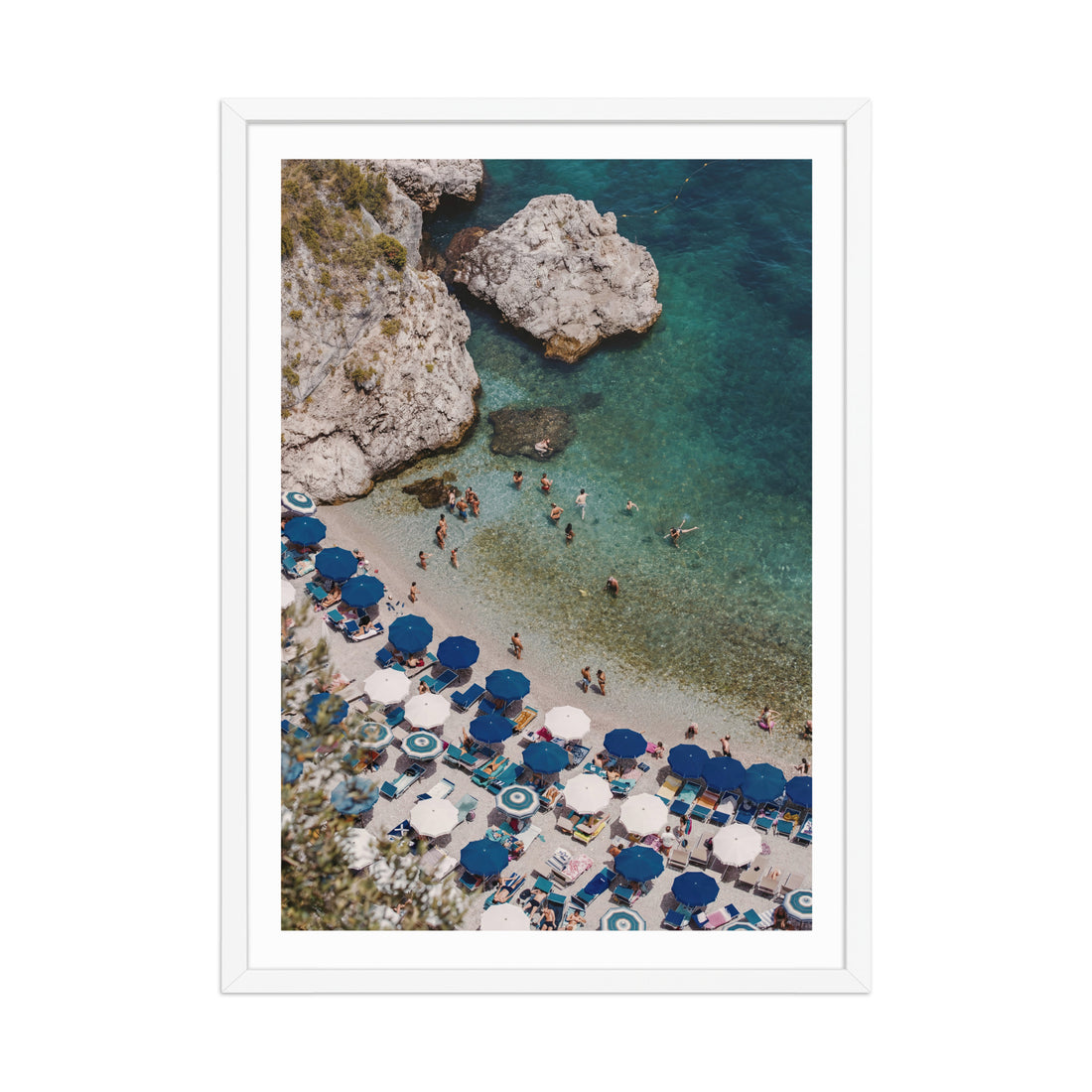 Beach scene with blue umbrellas and people near rocky shoreline